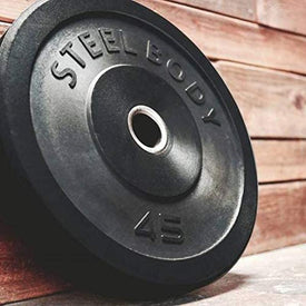 An Olympic bumper plate with a steel body and the text 'Steel Body' embossed on it, placed on a wooden surface.